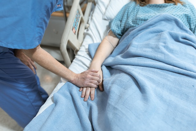 ER nurse holding patient's hand after they were able to find a travel nurse job in an emergency room