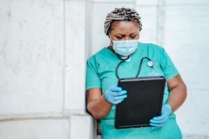 Nurse in scrubs looking at travel nurse salary per diem rates on tablet