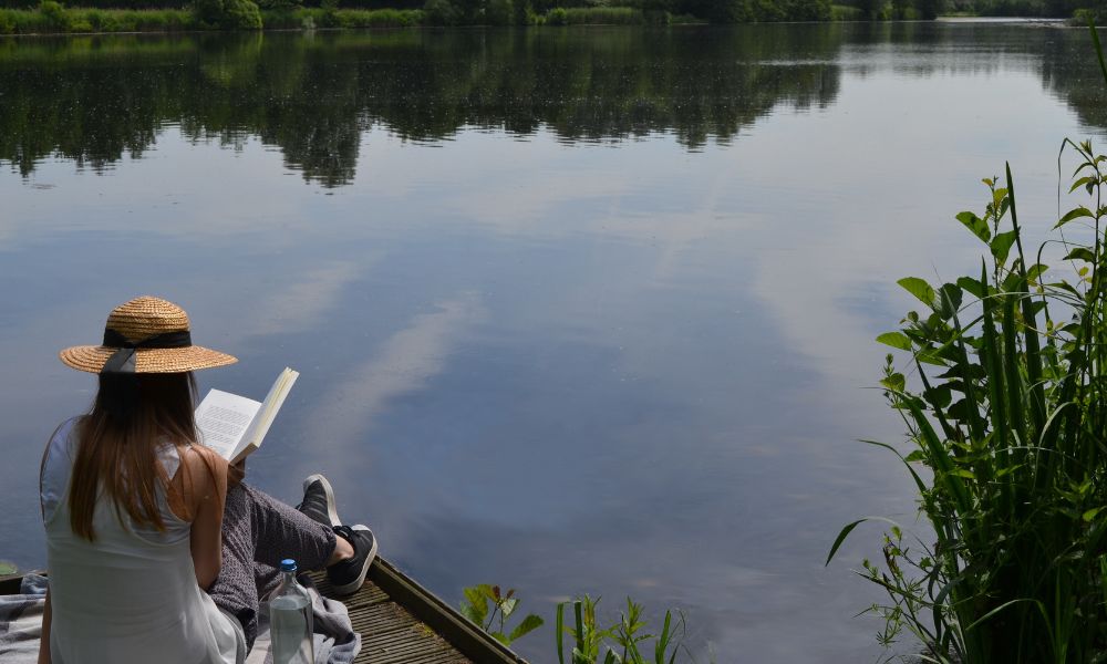 travel nurse across America reading beside a quiet lake